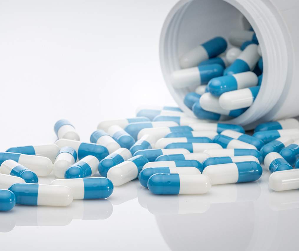 Blue-white antibiotic capsule pills spread out of plastic drug bottles